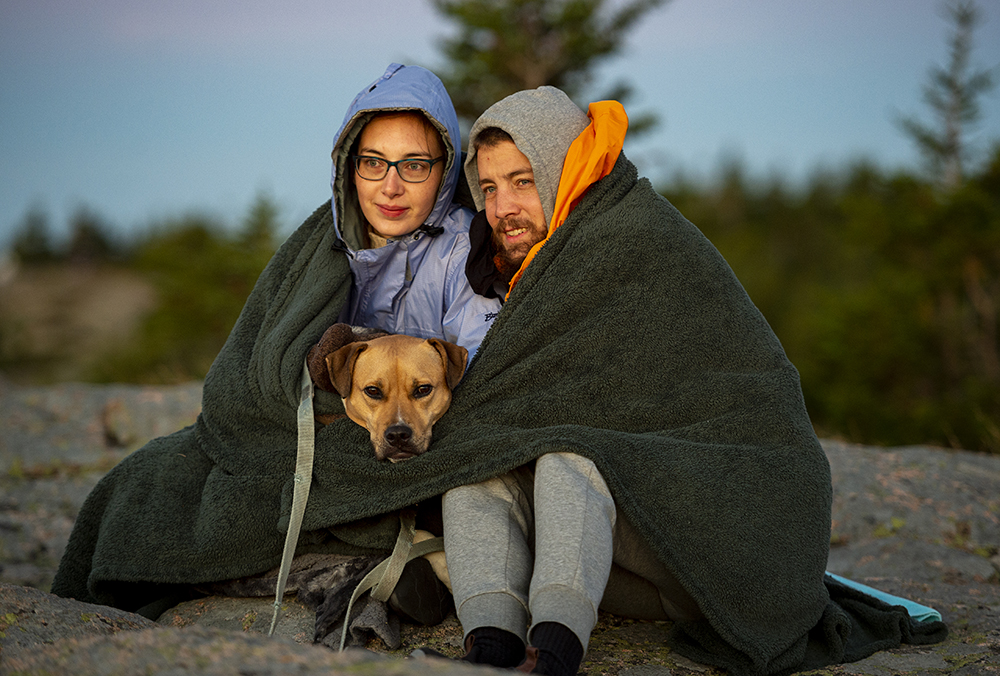 Park visitors Taylor Thompson and Russell Bloom wrap themselves and their dog Chloe in a blanket to stay warm while waiting for the sunrise on top of Cadillac mountain in Acadia National Park. 