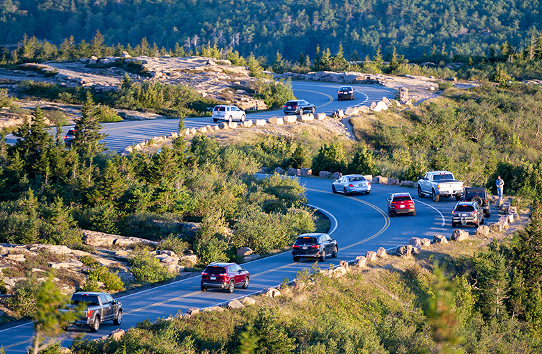 Cars drive down the Cadillac mountain road after viewing the sun rise in Acadia National Park