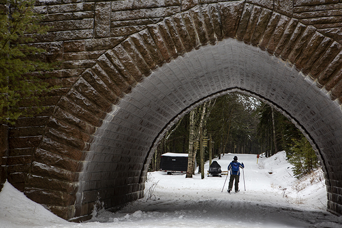 A cross country skier utilizes a freshly groomed Carriage Road around Eagle Lake in Acadia National Park
