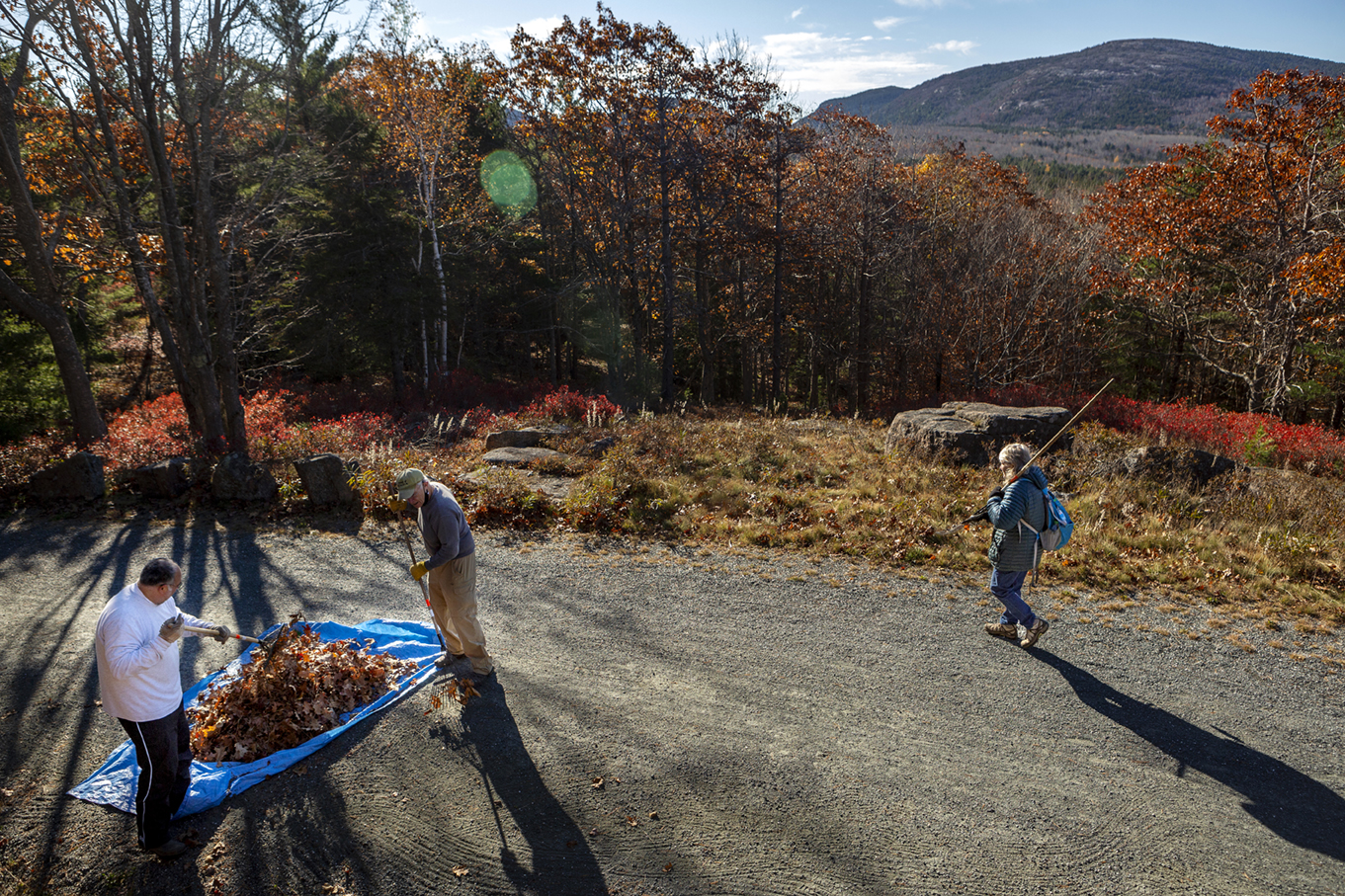 John Khairallah (left), and George Mitchell rack leaves onto a tarp while Billie Mitchell walks to a new section while working to clear leaves off the carriage road as part of the West Eden Friends volunteer during Friends of Acadia’s annual Take Pride in Acadia Day