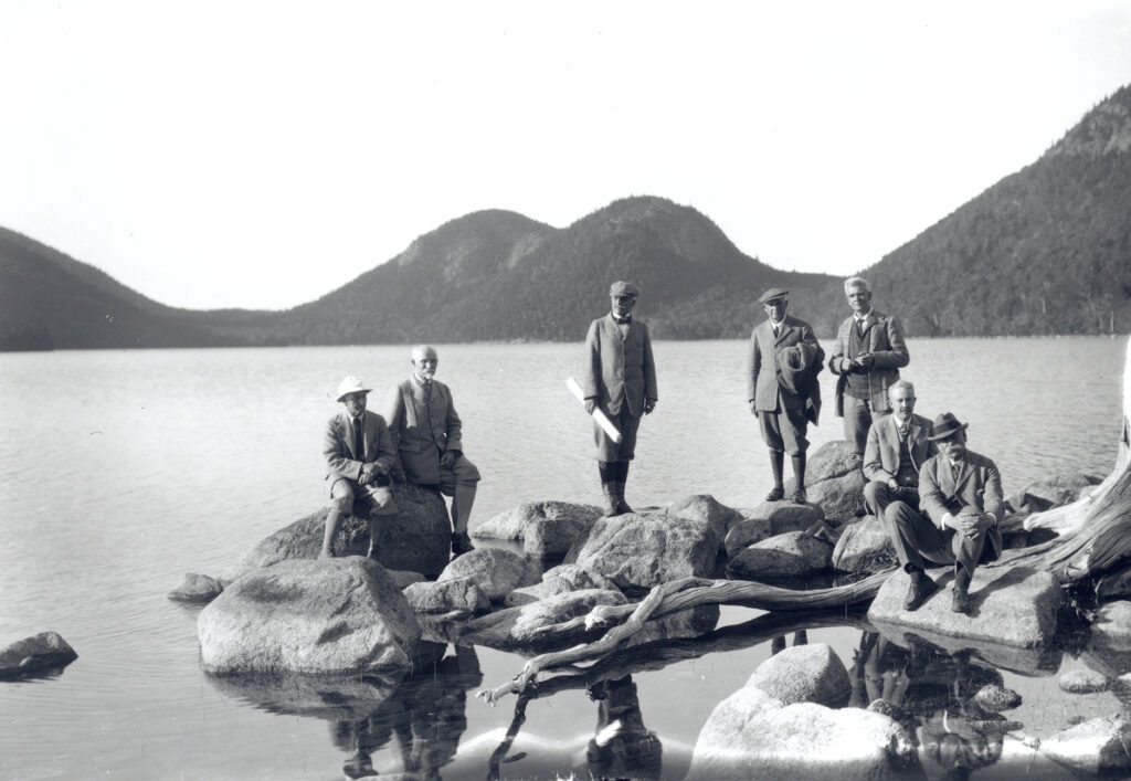 group of Founders of Acadia National Park standing on shore of Jordan Pond with the Bubbles in background.