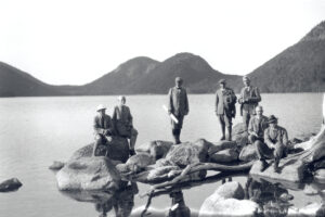 group of Founders of Acadia National Park standing on shore of Jordan Pond with the Bubbles in background.