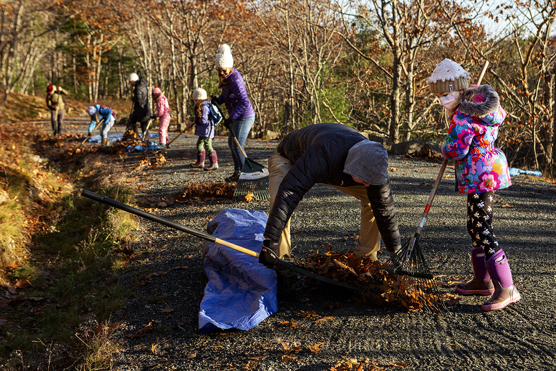 Nate Donaldson (center) helps Allie Donaldson, 6, clear leaves from the carriage road as part of Take Pride in Acadia Day